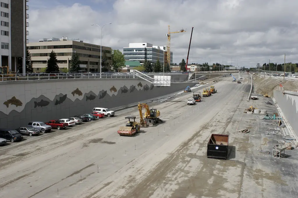 A view of an interstate construction site with trucks and cars.