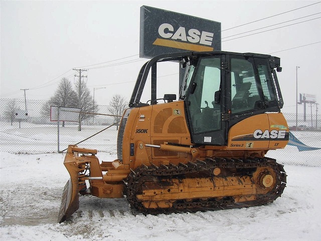 A yellow and black tractor is parked in the snow