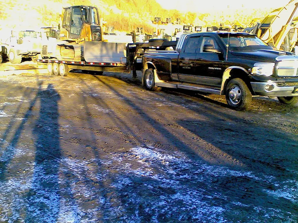 A truck pulling a trailer with a tractor on it.